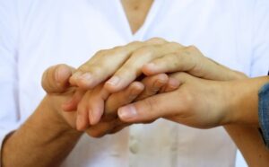 Profesional sosteniendo las manos de un paciente en el área clínica de neurología