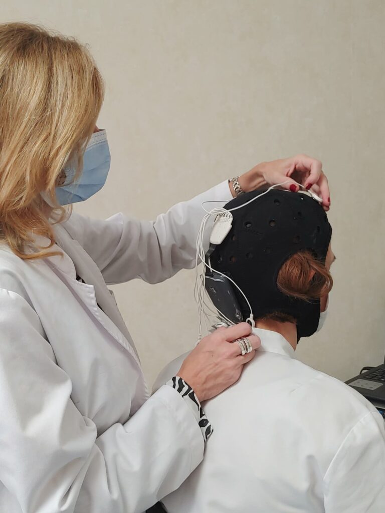 Profesional de INCIA colocando el casco de electrodos a una paciente para un tratamiento de tDCS
